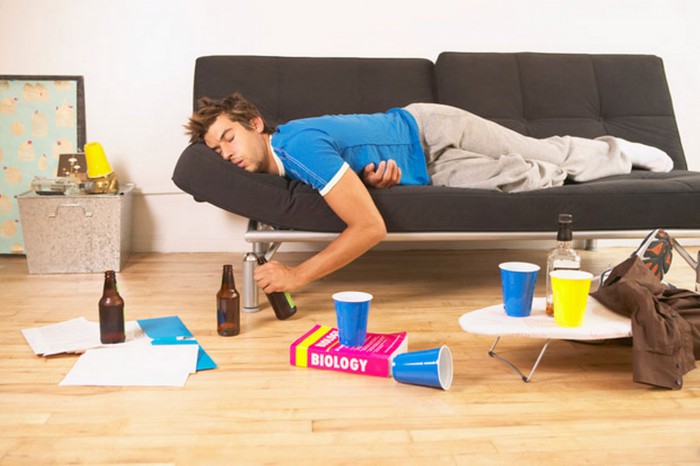 Young man passed out on couch, clutching beer bottle